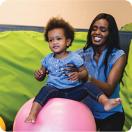 Parent balancing child on a ball